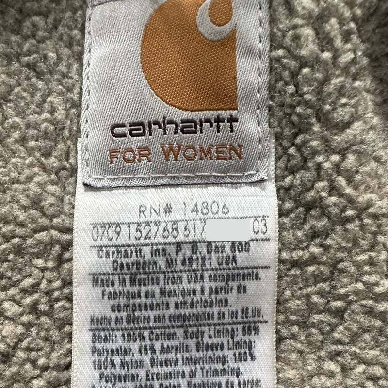 Una etiqueta de composición Carhartt con el código de fecha de cuatro dígitos 0709 al inicio de la línea debajo de RN 14806, con parte de esa línea tapada por privacidad