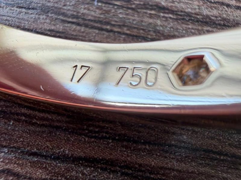Primer plano del interior de una pulsera de oro: el número de ley 750 estampado junto a la talla, 17