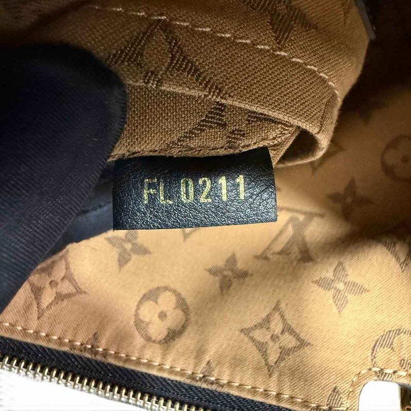Louis Vuitton-datumcode gestempeld op een zwart leren lipje tegen monogram-canvasvoering