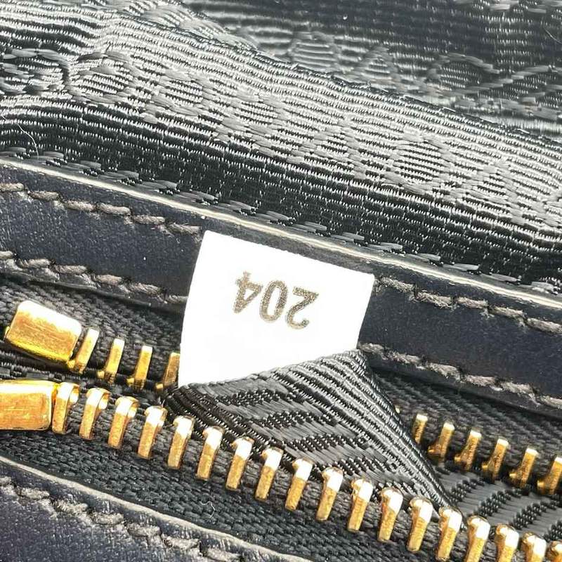 A Prada white tag and made in Italy label beside the zipper pull inside a bag, photographed in a mirror so the text reads backwards